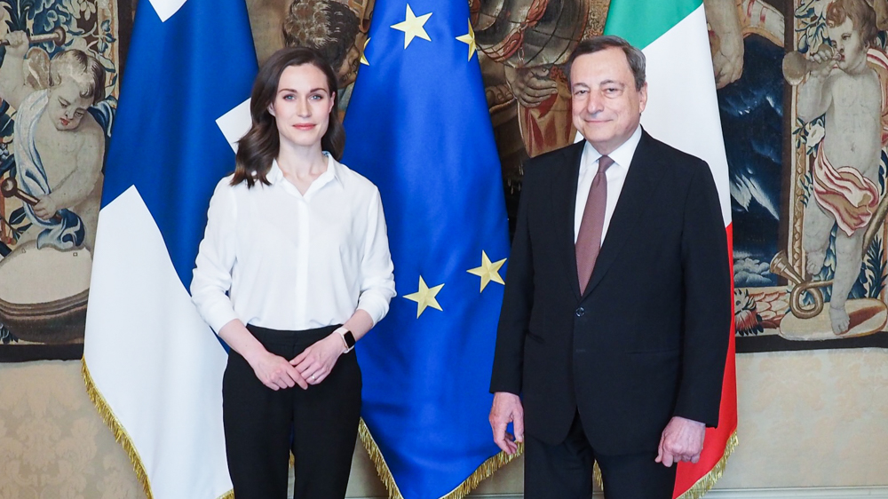 Prime Minister Sanna Marin and Italian Prime Minister Mario Draghi standing on the front of the Finnish, Italian and EU flags
