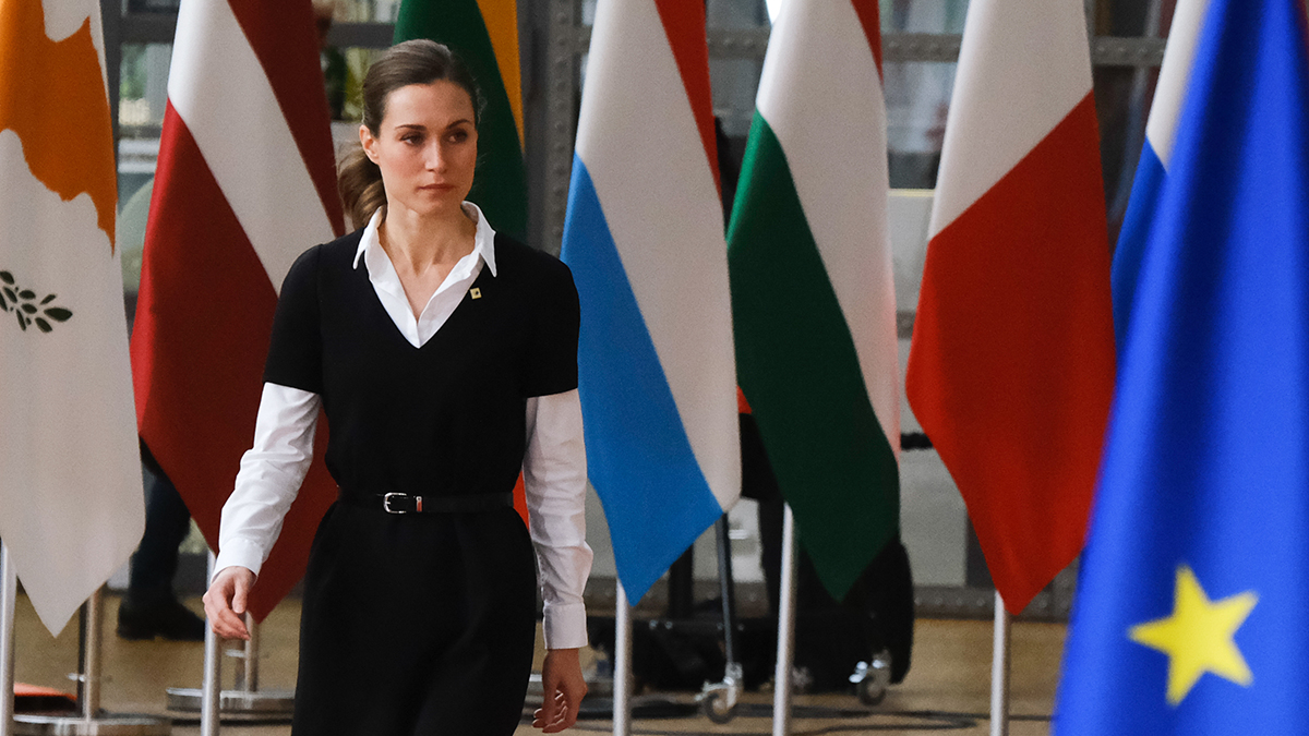 Pääministeri Marin kävelee Europa-rakennuksessa, lippuja taustalla