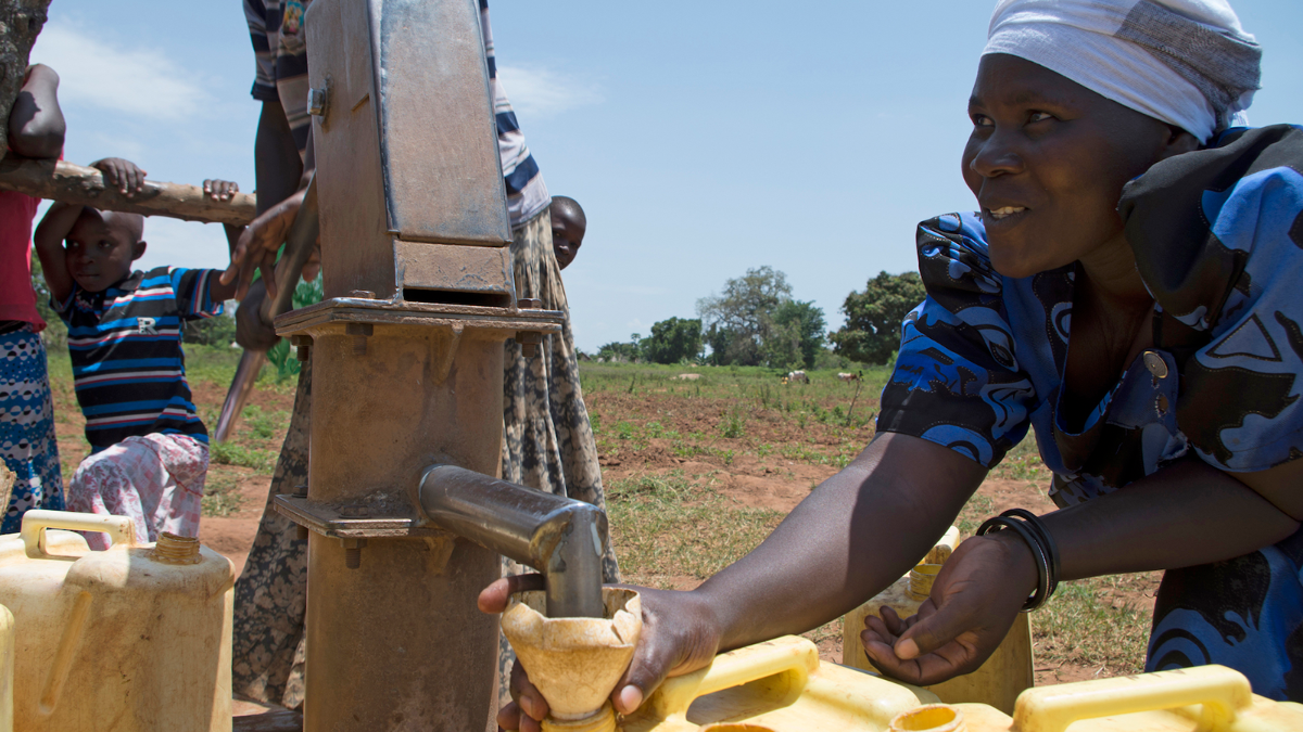 Nainen Ugandassa ottamassa puhdasta vettä laitteesta.